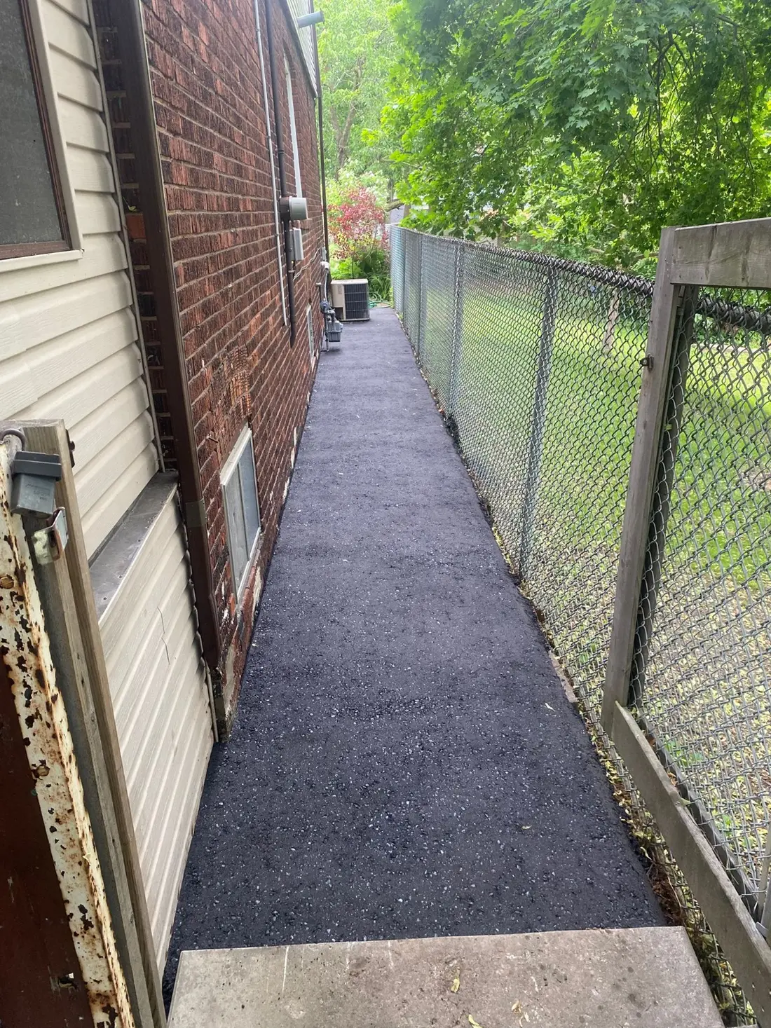 Fresh asphalt path along the side of a residential property